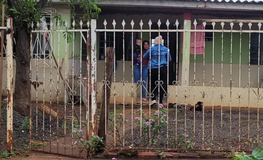 Mãe com uma criança no colo recebendo pão atrás do portão