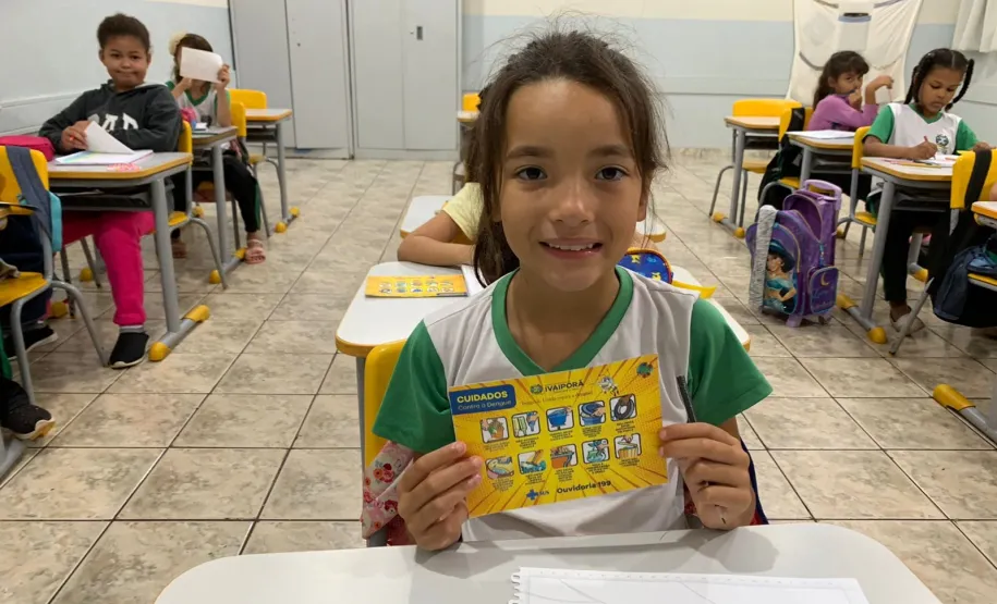 Crianças com folheto informativo da Dengue.
