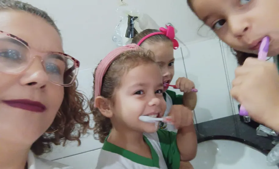 Auxiliar Bucal realizando trabalho de saúde bucal com as crianças.